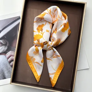 Elegant white silk scarf with orange flower prints displayed on a luxury jewelry tray