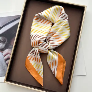 Detalle de un elegante pañuelo de seda con estampado ondulado naranja en una bandeja
