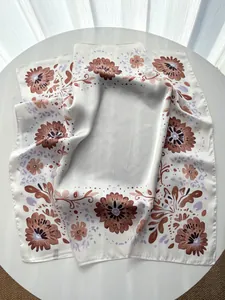 Close-up of elegant floral silk scarf texture with detailed cream and brown flower patterns