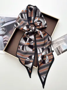 Détail d'un foulard en satin noué en boucle avec motifs de chevaux et de chaînes