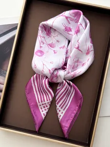 Detail of floral silk scarf with pink and purple bouquet patterns on a gold tray
