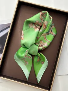 Detail of light green silk scarf with apricot blossoms in artistic floral print
