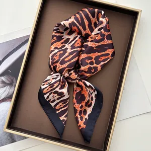 Detail of silk leopard print scarf with black borders on a premium leather tray