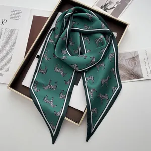 Detailaufnahme des dunkelgrünen Seidenschals mit Zebramuster auf einem eleganten Tablett