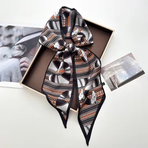 Détail d'un foulard en satin de soie à motif géométrique noué en boucle sur un plateau