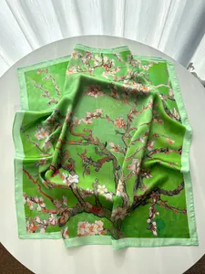 Detail view of silk scarf with green Van Gogh almond blossom print on white table