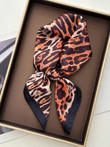Close-up of leopard print silk scarf tied in a bow on a luxury tray background