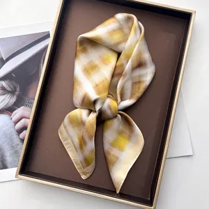 Elegante zijden sjaal met geel en bruin ruitpatroon op een vintage dienblad