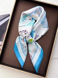 Detailed close-up of floral print silk scarf with light blue border in luxury display