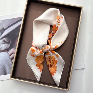 Close-up of elegant floral silk scarf tied in a bow inside a premium gift box