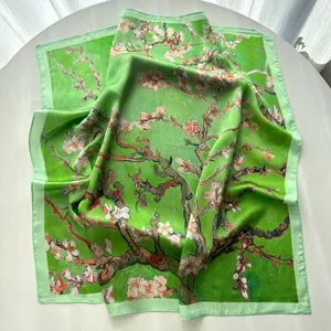 Macro shot of green floral silk scarf with almond blossom patterns and fine hem detail