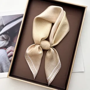Close-up of a beige polka dot silk scarf tied as a bow in a premium gift box