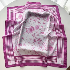 Detail of a white square scarf featuring pink floral prints and elegant striped borders