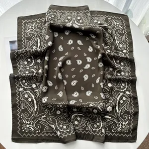 Close-up of brown silk square scarf with white paisley pattern on a white table
