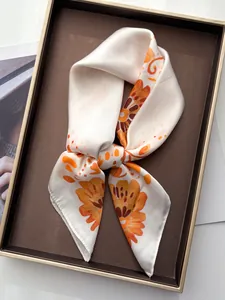 Close-up of floral silk scarf with orange flower patterns on a display tray