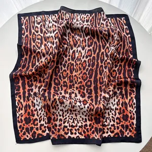 Macro detail of silk-satin leopard print scarf with bold orange and black border