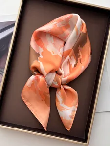 Detail shot of silk-like scarf with orange floral prints and smooth draped texture