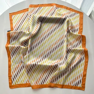 Detalle macro del elegante estampado ondulado en el pañuelo de seda satinada con borde naranja