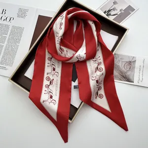 Close-up of red twilly silk scarf featuring horse carriage print and 100% polyester label