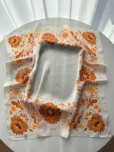 Close-up of elegant floral silk scarf featuring orange blossoms and satin texture