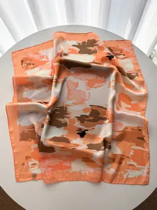 Macro shot of French-style floral silk scarf with vibrant orange camouflage print on a table