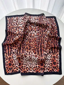 Detail view of leopard print silk scarf with luxury black border and smooth texture