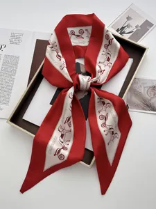 Detail of red silk twilly scarf with carriage print and beveled edges in a gift box