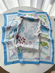 Close-up of silk square scarf with blue border and tropical floral shell print details
