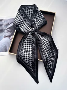 Détail d'un foulard en soie pied-de-poule noué en boucle sur un plateau de présentation