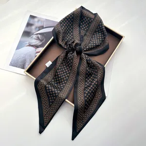 Detailed close-up of a satin silk scarf with vintage horseshoe print on a display tray