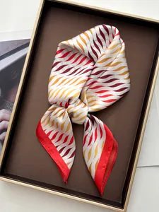 Detalle de un elegante pañuelo de seda con estampado de ondas rojas y amarillas en bandeja