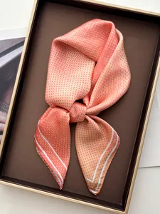 Detailed view of peach polka dot silk scarf elegantly knotted in a golden trim gift tray