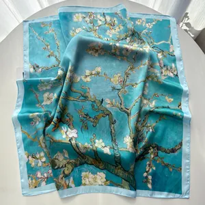 Close-up of sky blue silk scarf featuring blooming almond blossom art on white table