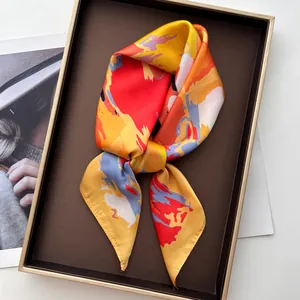 Detail view of a luxury satin square scarf with colorful abstract floral prints on a tray