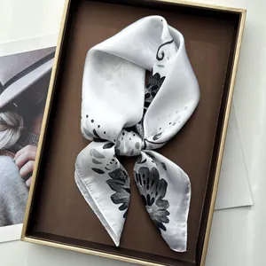 Detailed close-up of elegant silk scarf with black floral print on a display tray
