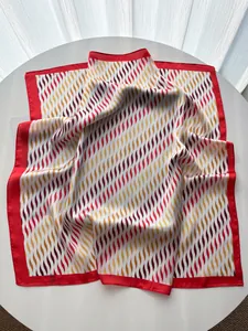 Detalle de pañuelo de seda con estampado ondulado rojo y naranja sobre fondo blanco