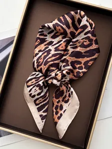 Macro view of leopard print silk scarf with satin finish and beige rolled edges in a tray