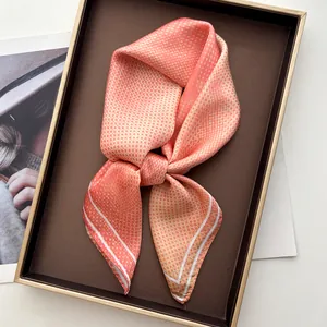Close-up of coral pink satin scarf with white polka dots and elegant border details