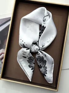 Detail of elegant white silk scarf with floral print and high-quality hemmed edges