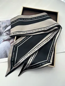 Détail d'un foulard en soie noir et beige avec texte sur un plateau doré élégant