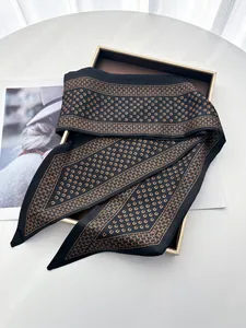 Detail of luxury horseshoe print black silk twilly scarf draped on a gift display box