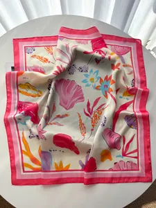 Detailed view of floral shell print silk scarf with pink borders on a table