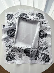 Detail view of smooth silk texture and vintage black floral print on white square scarf