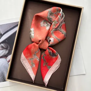 Detail of coral silk scarf with Van Gogh plum blossom print on a display tray