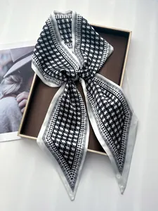 Détail d'un foulard en soie à motif pied-de-poule noir et blanc sur un plateau