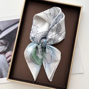 Détail d'un foulard en soie à imprimé floral avec couture fine dans une boîte cadeau