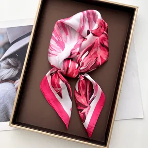 Close-up of elegant monstera leaf print silk scarf folded in a luxury gift display box