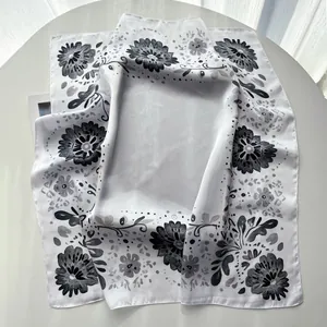 Detail of floral printed silk scarf with elegant black hand-drawn flowers on white fabric