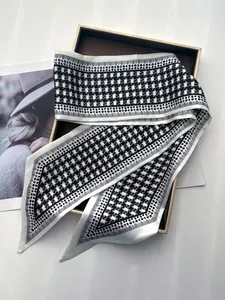 Détail d'un foulard étroit en soie à motif pied-de-poule sur un coffret cadeau