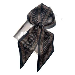 Satin silk scarf featuring brown horseshoe pattern tied in bow on gray gift box